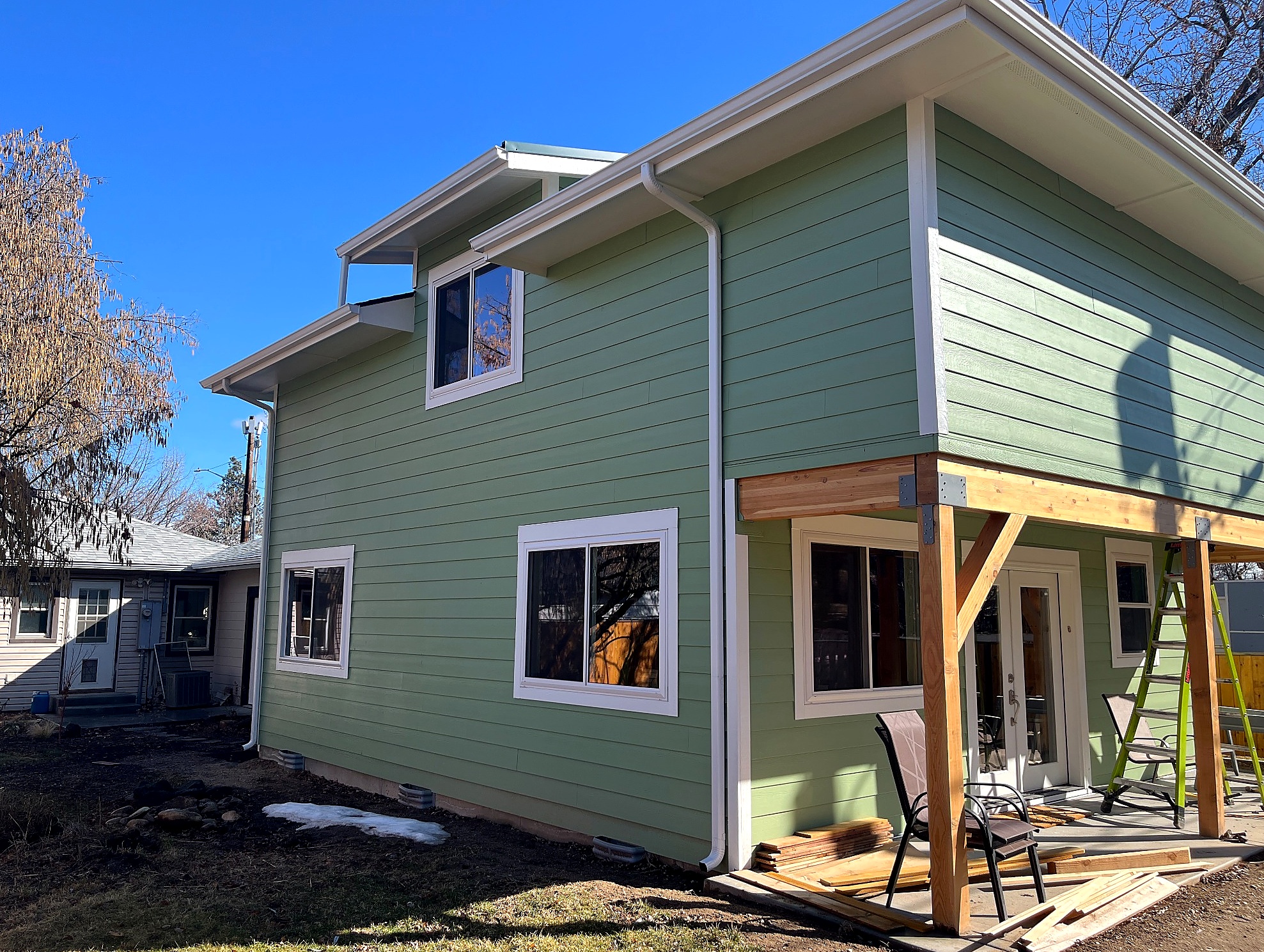 Finished Brookman ADU exterior with the upper dormer volume, covered patio, and completed green siding.